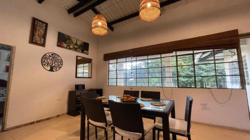 Un comedor con mesa y sillas y ventanas. en Finca Buenavista Sasaima, en Sasaima