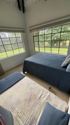 two beds in a room with two windows at Finca Buenavista Sasaima in Sasaima