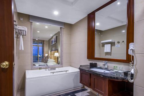 a bathroom with a tub and a sink and a mirror at Avatar Valley Grand Hotel in Zhangjiajie