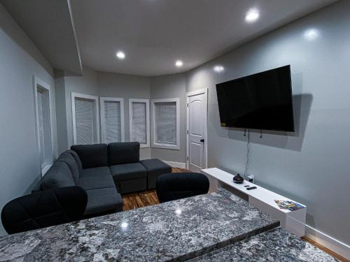 a living room with a couch and a flat screen tv at Modern 3BR Walk to Subway 2 Min to LOGAN Airport in Boston