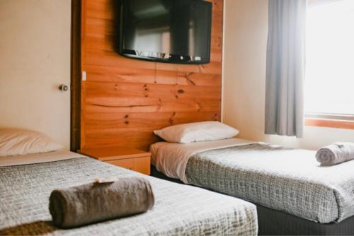 zwei Betten in einem Hotelzimmer mit einem Fernseher an der Wand in der Unterkunft Bega Grand Hotel in Bega