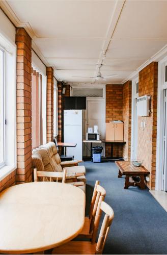 a living room with a table and a kitchen at Bega Grand Hotel in Bega