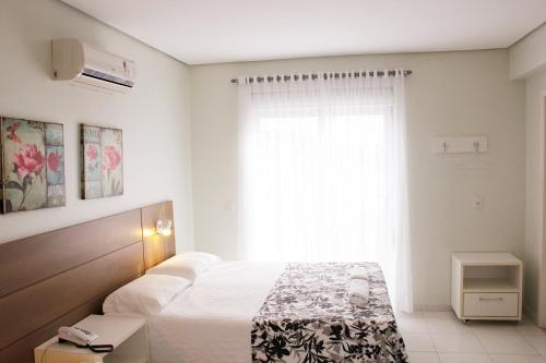 a bedroom with a bed and a large window at Hotel Porto Madero in Florianópolis