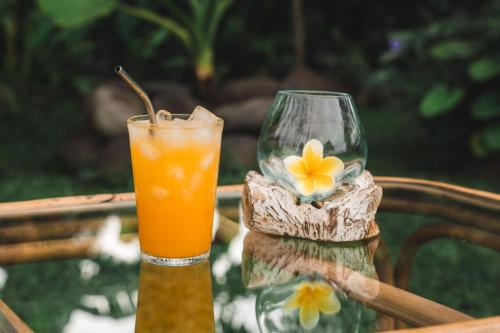 a drink on a table with a flower in a vase at Batu Kayu Medewi in Medewi