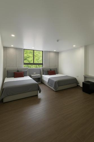 two beds in a large room with two windows at Hoàng Huy Hotel in Cat Ba