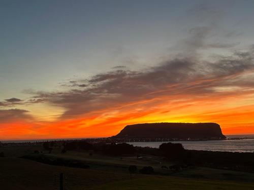 un coucher de soleil sur l'océan avec une montagne en arrière-plan dans l'établissement Beachscape, à Stanley
