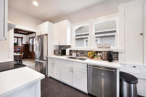 a kitchen with white cabinets and a stainless steel refrigerator at Sunny 3BR Home Near UW & Children Hospital Gym in Seattle