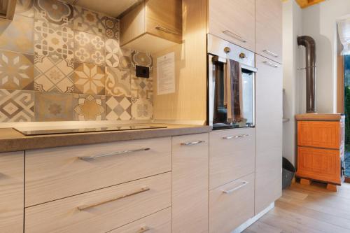 a kitchen with wooden cabinets and tiles on the wall at Appartamento Saone in Ragoli