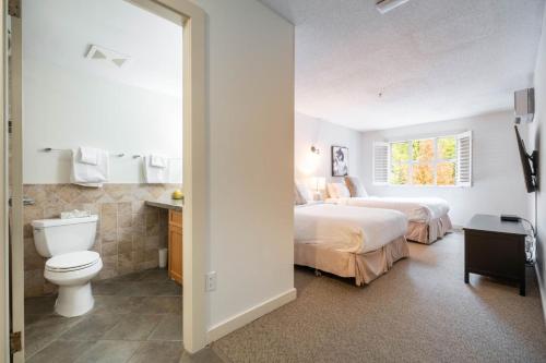 1 dormitorio con 2 camas, aseo y ventana en Glacier Lodge 216 by Outpost Whistler, en Whistler