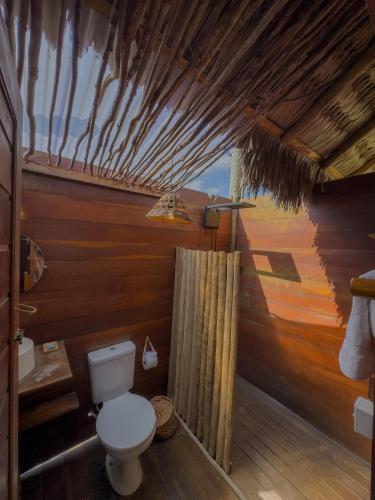 a bathroom with a toilet and a wooden wall at Kitesurf Life Arpoador da Tutoia in Tutóia