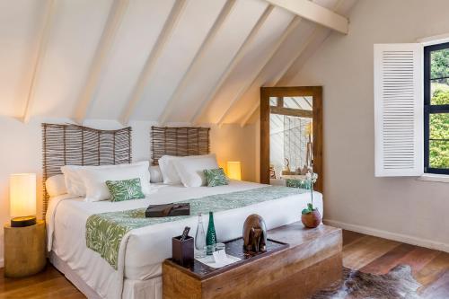a bedroom with a large bed and a mirror at Santa Teresa Hotel Rio de Janeiro - MGallery Collection in Rio de Janeiro