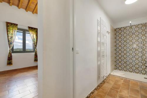 a bathroom with white walls and a glass door at Fattoria le Caprine in Querce