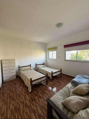 a room with three beds and a window at Depto Santa Cruz in Villa Santa Cruz del Lago