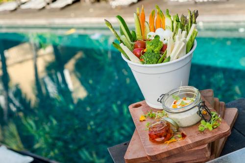 a bucket of vegetables on a table next to a pool at Santa Teresa Hotel Rio de Janeiro - MGallery Collection in Rio de Janeiro