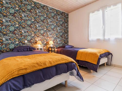 two beds in a room with floral wallpaper at Maison traditionnelle, proche plages, WIFI, jardin - FR-1-306-1319 in Fresnay-en-Retz