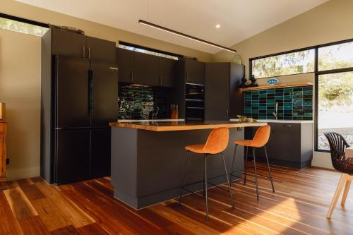 a kitchen with black cabinets and orange bar stools at Parachilna at Boardwalk Villas Metung in Metung