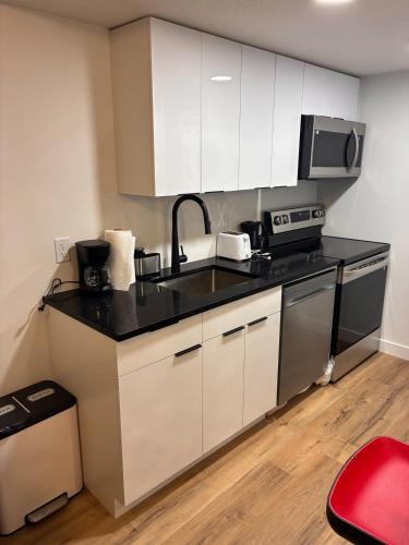 a kitchen with white cabinets and a black counter top at Home away from Home in Edmonton