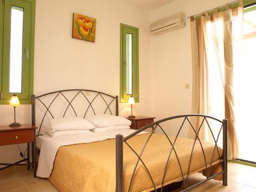 a bedroom with a bed with two tables and two windows at Villa Alexander in Gennadi