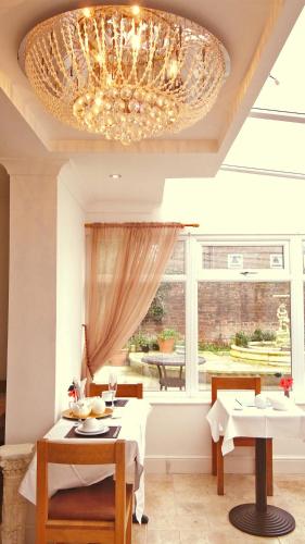 a dining room with a chandelier and a table and chairs at Jessamine House Hotel in Gravesend