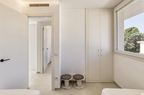 a bedroom with white walls and a window and two stools at Penthouse l'Escala in L'Escala