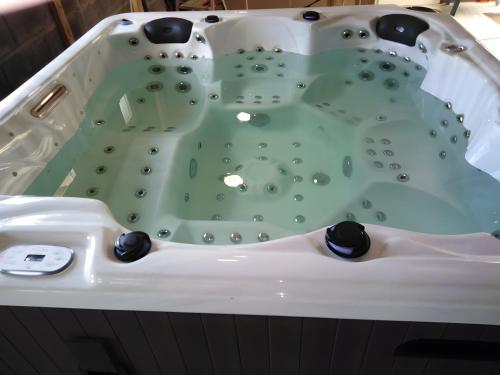 a white bathtub with a green floor and black fixtures at A l oree du bois in Signy-lʼAbbaye
