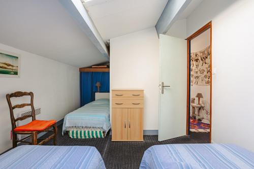 a small bedroom with two beds and a chair at Les Oyats in La Couarde-sur-Mer