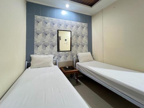 - 2 lits dans une chambre avec un miroir mural dans l'établissement Huiz de Rico Guesthouse Syariah near Ambarrukmo Area, à Demangan