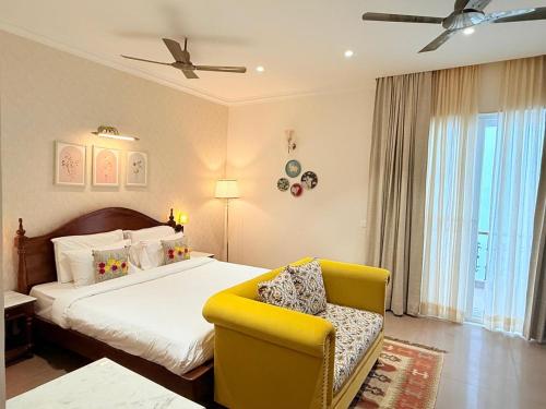 a bedroom with a bed and a yellow chair at Madhukar Vilas in Vrindāvan