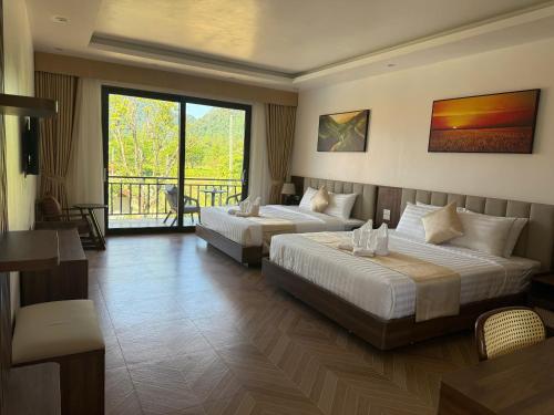 une chambre d'hôtel avec deux lits et un balcon dans l'établissement Paradise Mountain View Resort, à Vang Vieng