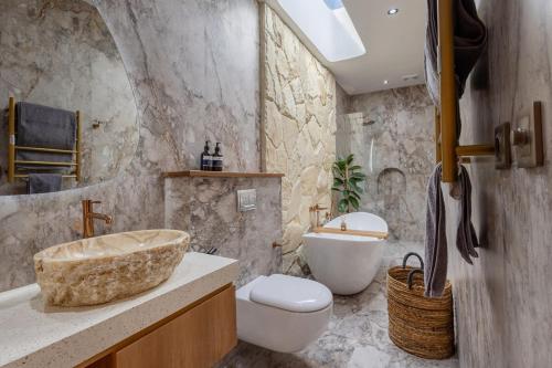 a bathroom with a sink and a toilet and a tub at Villa Nida Premium by Tofino Villas in Uluwatu