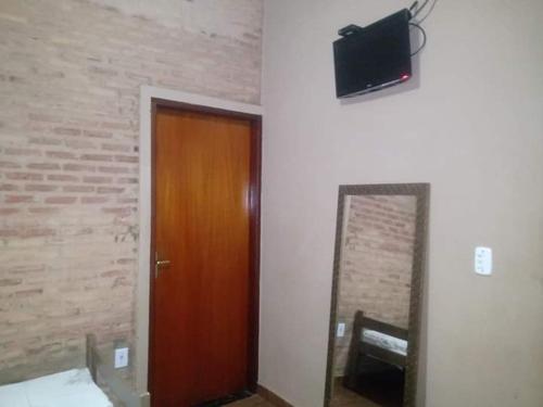 a room with a door and a mirror and a television at Hotel Pousada Trevo in Barretos
