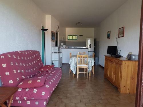 Una sala de estar con un sofá y una mesa y una cocina. en Appartement avec Terrasse Vue Mer, en Propriano