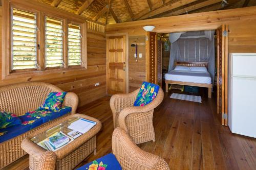 ein Wohnzimmer mit Stühlen und ein Bett in einer Hütte in der Unterkunft SeaScape on Heavenly Bay in Castara