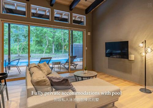 Una sala de estar con un sofá y un televisor. en 秩父別邸 木叢 komura, en Chichibu