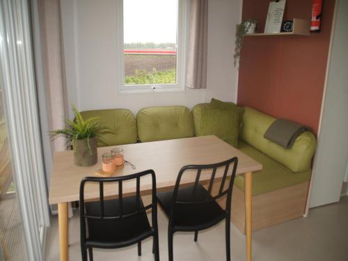 Una pequeña habitación con una mesa, sillas y un sofá. en Holiday home in Schoonloo with balcony terrace, en Schoonloo