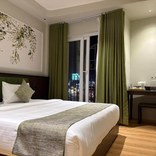 a bedroom with a bed with green curtains and a window at SandDune Luxury Suites in Cochin