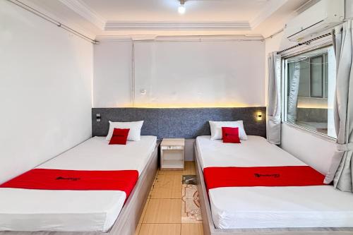 RedDoorz near Alun Alun Subang 2 في سوبانج: سريرين في غرفة صغيرة مع وسائد حمراء