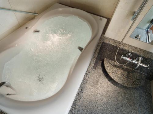 a bath tub filled with water in a bathroom at Hotel Metropolitan Tokyo Ikebukuro in Tokyo