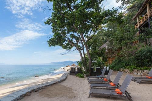 a row of chaise lounge chairs on a beach at Xinalani Retreat Mexico in Qumiste