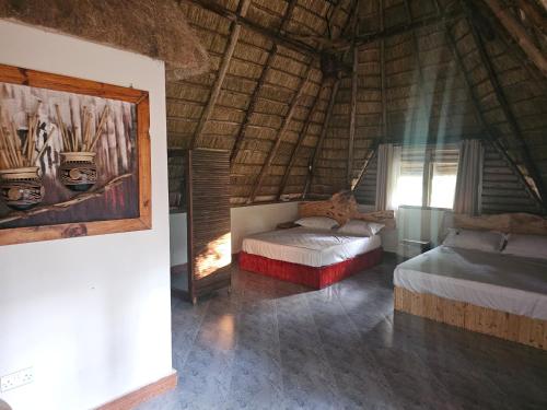 a bedroom with two beds and a painting on the wall at Nguru Farm Cottages in Kabale