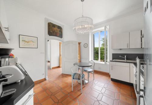 a kitchen with white cabinets and a table and a stool at Villa Alexandre III in Dijon