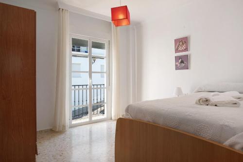 Un dormitorio con una cama y una ventana grande. en Casa Begines, en Vejer de la Frontera