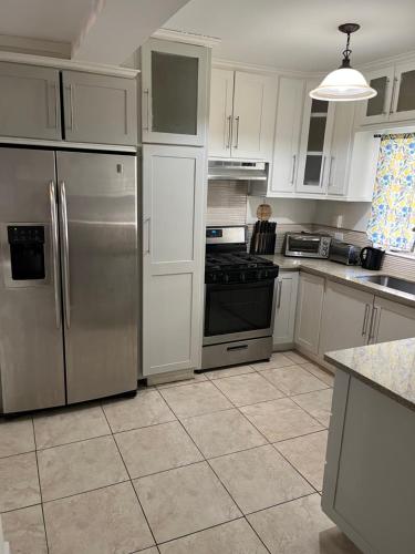 Una cocina con gabinetes blancos y electrodomésticos de acero inoxidable. en comfortable 3bedroom townhouse, en Curepe