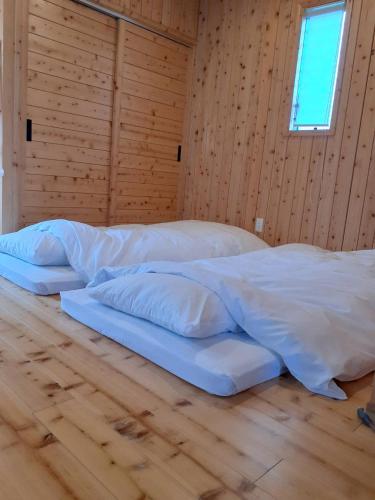 two beds in a room with wooden walls at アグリート島時間 in Onomichi
