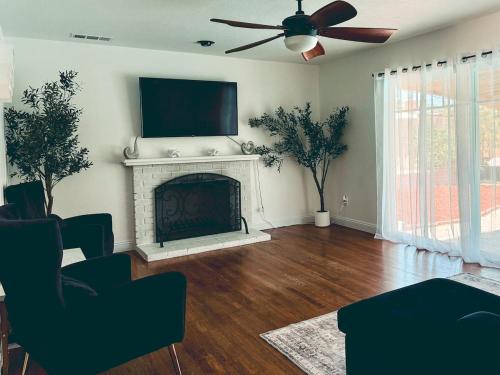 Una sala de estar con chimenea y ventilador de techo. en Modern SD Oasis with Pool & HotTub, en San Diego