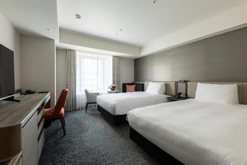 a hotel room with two beds and a television at Hotel Nikko Fukuoka in Fukuoka