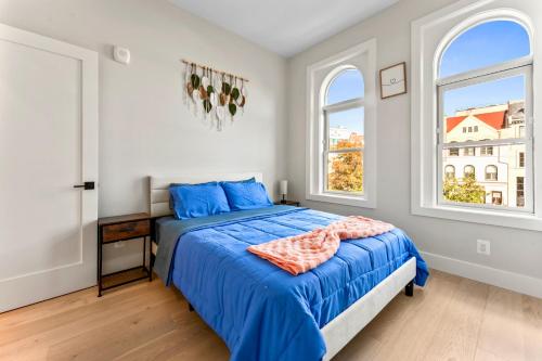 a bedroom with a bed with blue sheets and two windows at 2Bedroom Condo with Private patio in Downtown DC Dupont in Washington