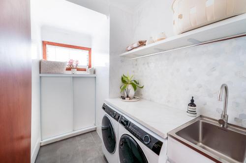 BaeView - Panoramic Group Stay Above Encounter Bay في Encounter Bay: مطبخ مع حوض وغسالة ملابس