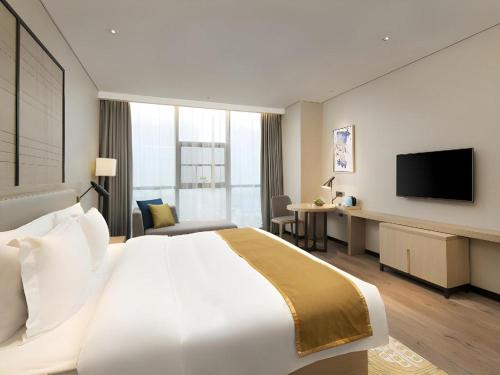 a hotel room with a large bed and a television at Echarm Hotel Changsha Gaoqiao in Changsha