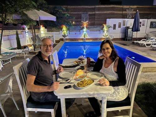 a man and woman sitting at a table in front of a pool at Flower of life guest house in Luxor